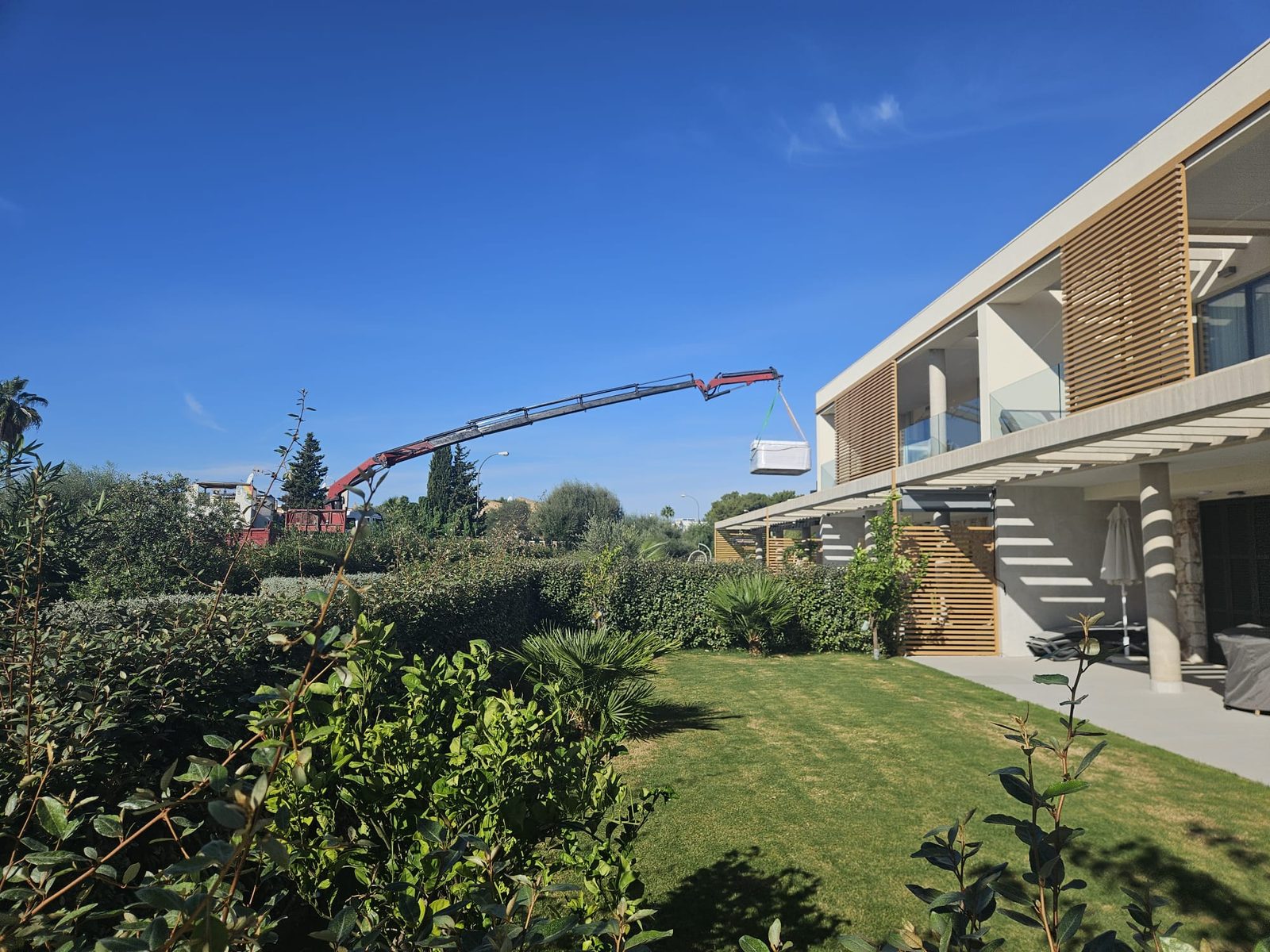 The mobile crane lifting the whirlpool over the garden towards the roof terrace in Sa Vinyola, Campos