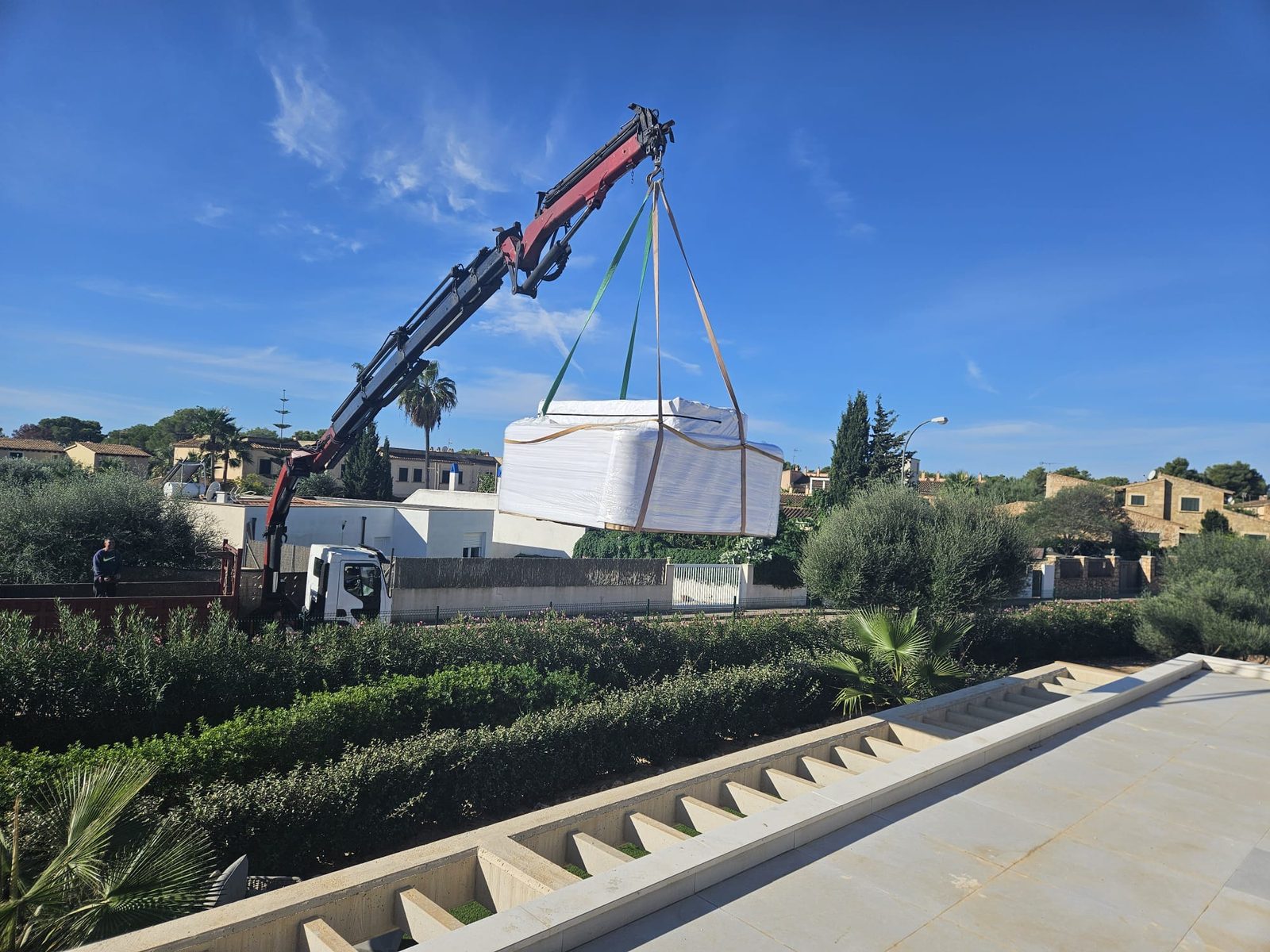 The wrapped Relax hanging from the mobile crane above the hedge on its way to the roof terrace