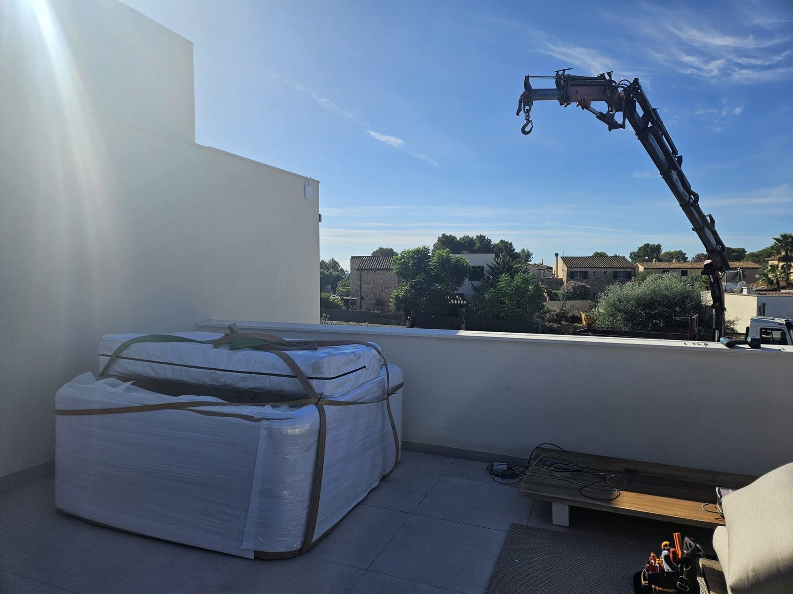 The wrapped whirlpool set down on the roof terrace with the crane boom still over the parapet