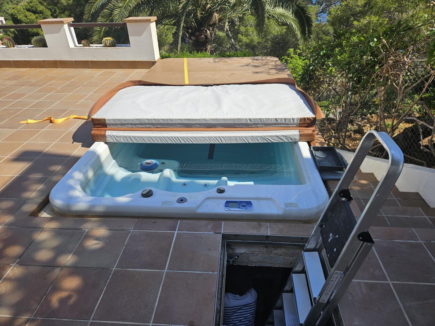 Spa set into a tiled terrace in Costa Canyamel, Mallorca, with the cover opened for service