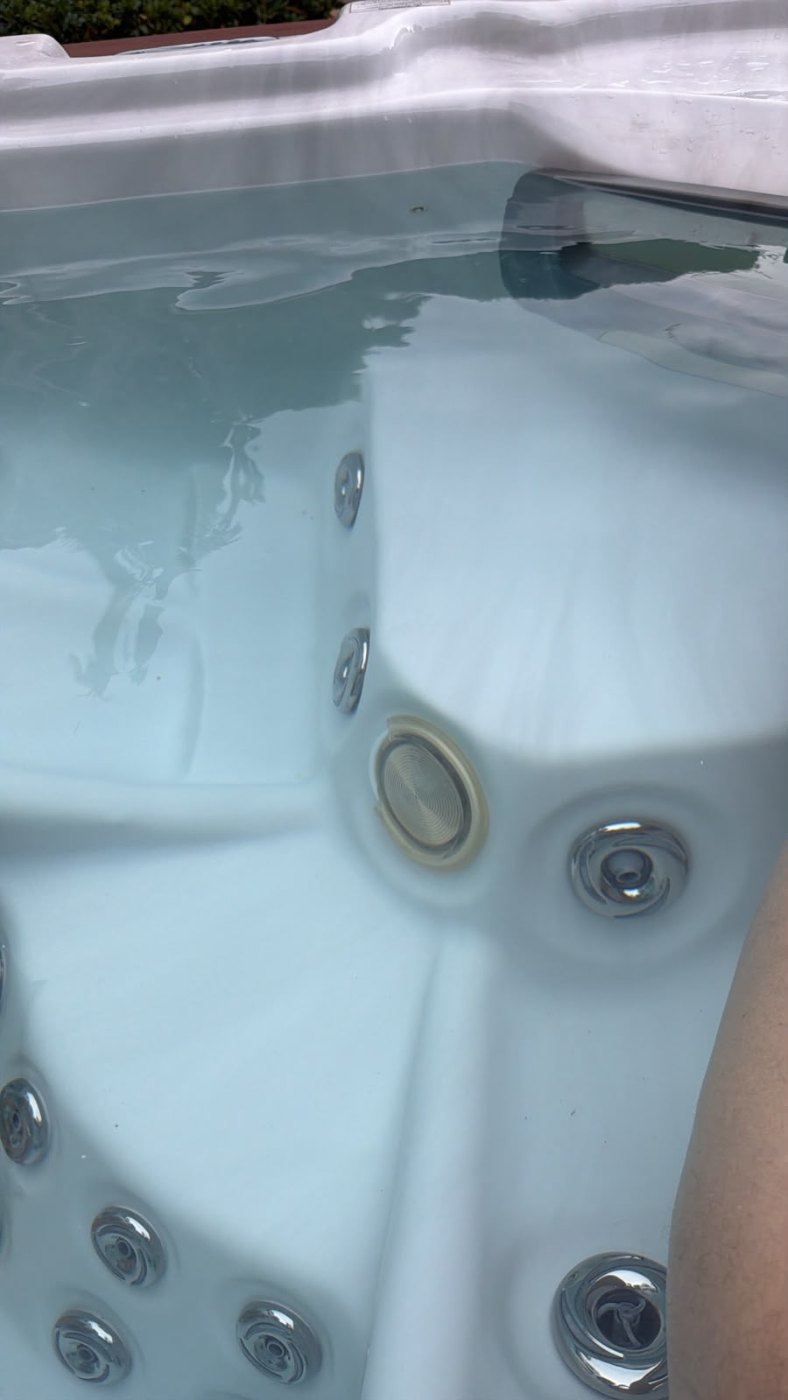The damaged lamp fitting under water in the filled spa, the lens sitting loose in its housing