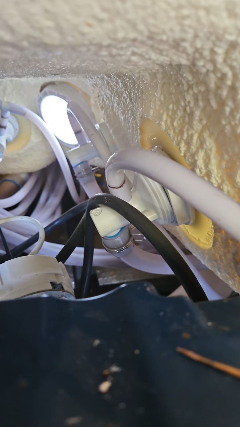 Pipework and wiring in the technical bay behind the shell while the whirlpool light is tested