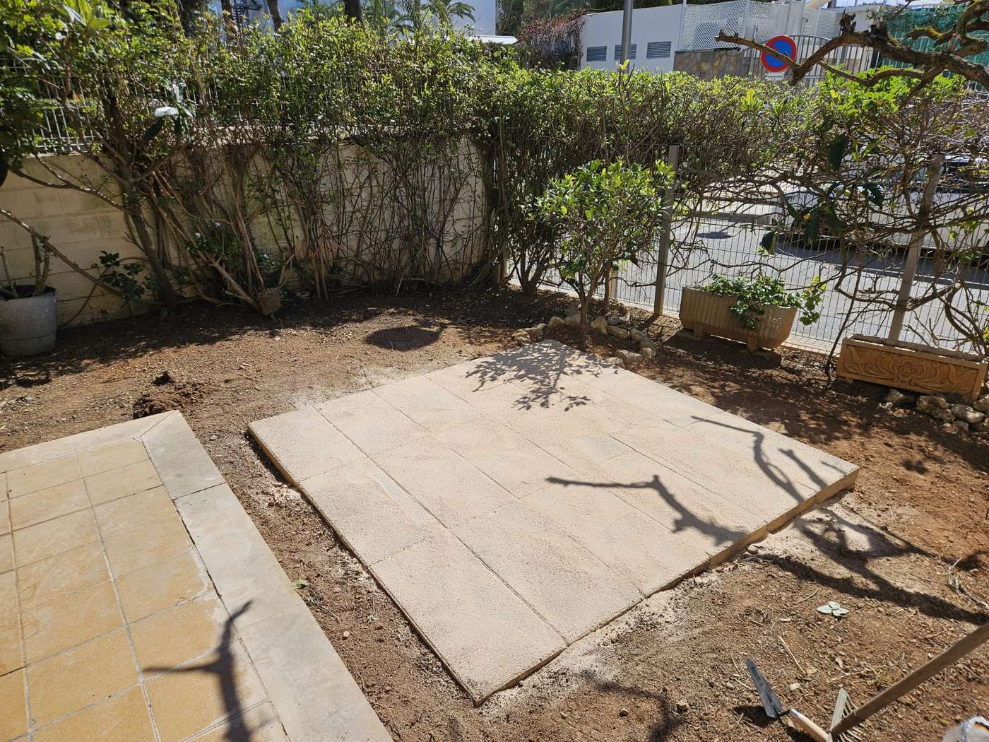 Losas de hormig&oacute;n asentadas sobre arena y grava formando la base nivelada y desmontable del jacuzzi en un jard&iacute;n de Las Maravillas