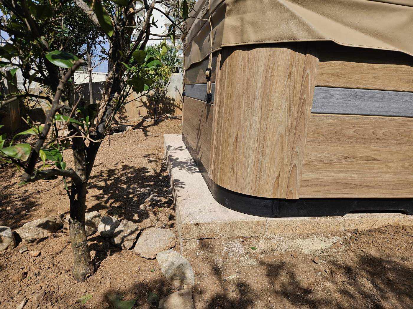Detalle del mueble del jacuzzi sobre la base de losas terminada, con el borde del jard&iacute;n al lado