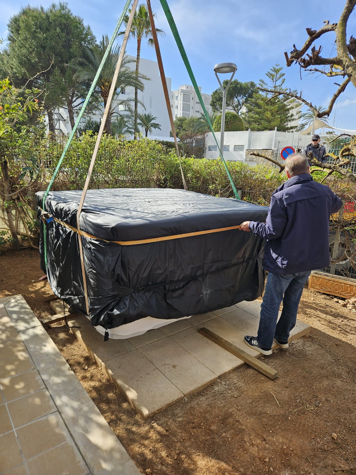 El equipo guiando el jacuzzi hasta la base de losas preparada