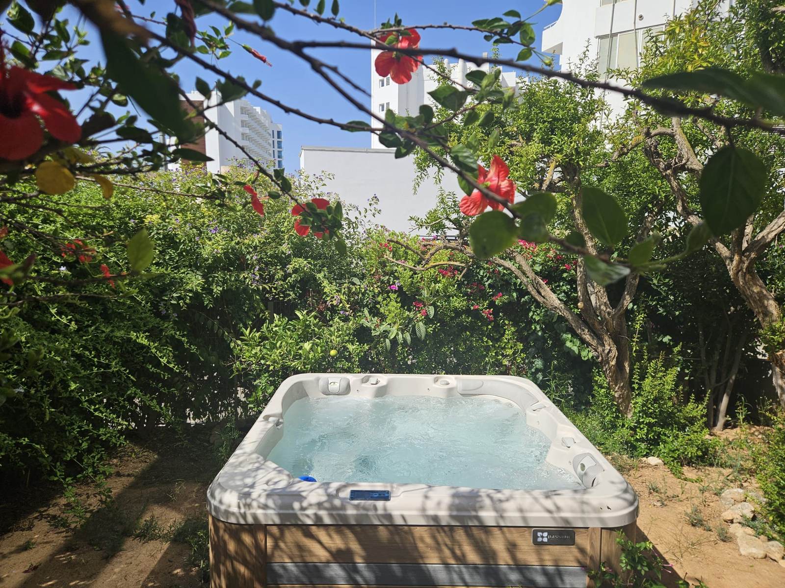 Jacuzzi Waterwave Relax terminado en el jard&iacute;n de una planta baja, enmarcado por buganvilla, en Las Maravillas, Playa de Palma, Mallorca