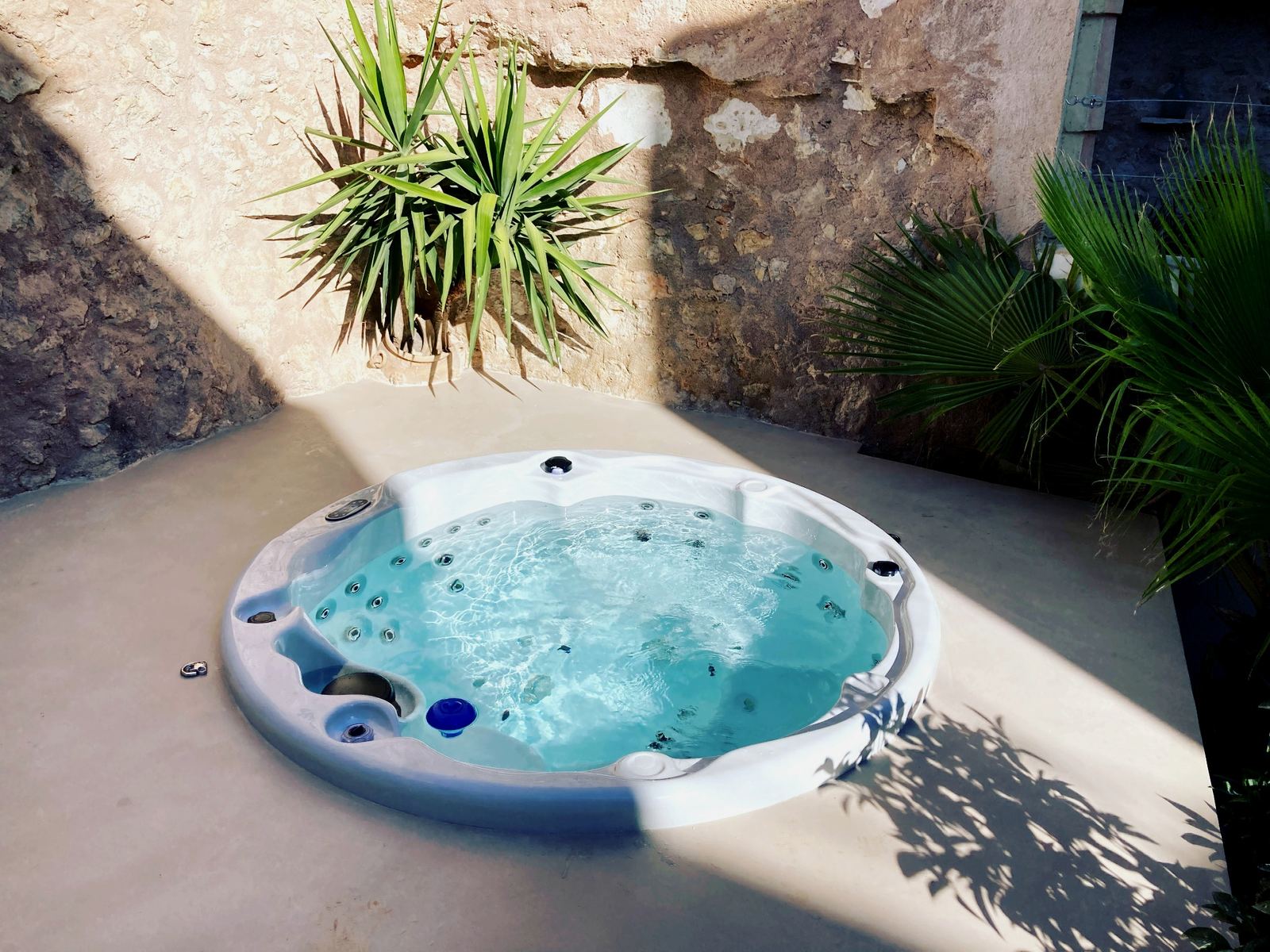 Round garden hot tub tucked between Mediterranean plants in Andratx