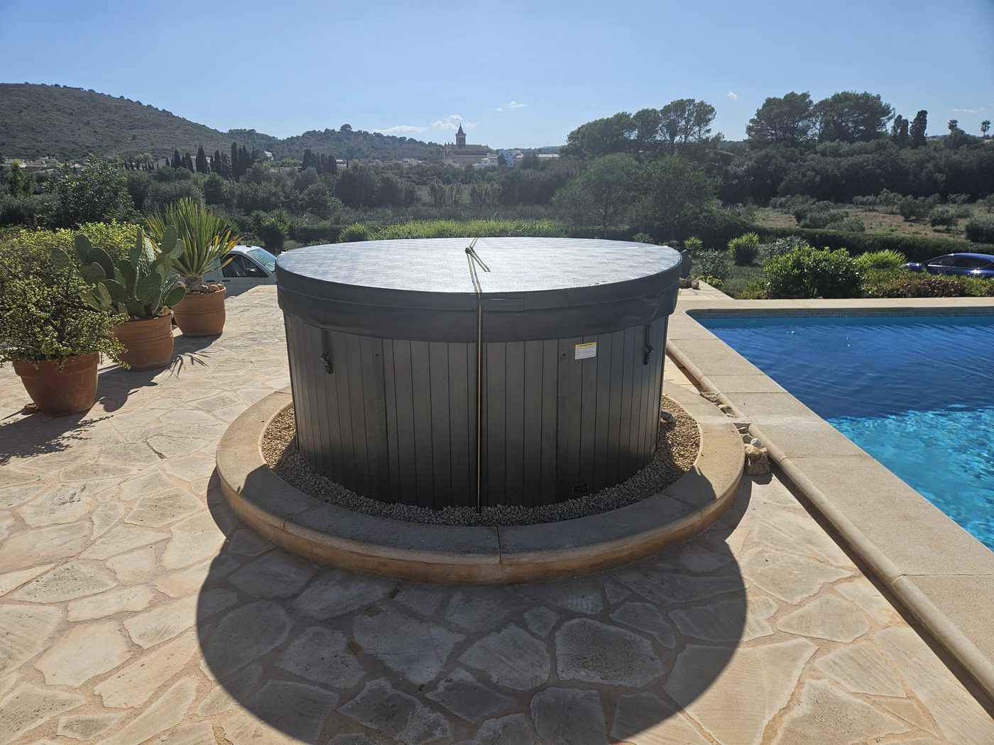 Whirlpool mit grauer Thermoabdeckung und Spanngurten am Pool