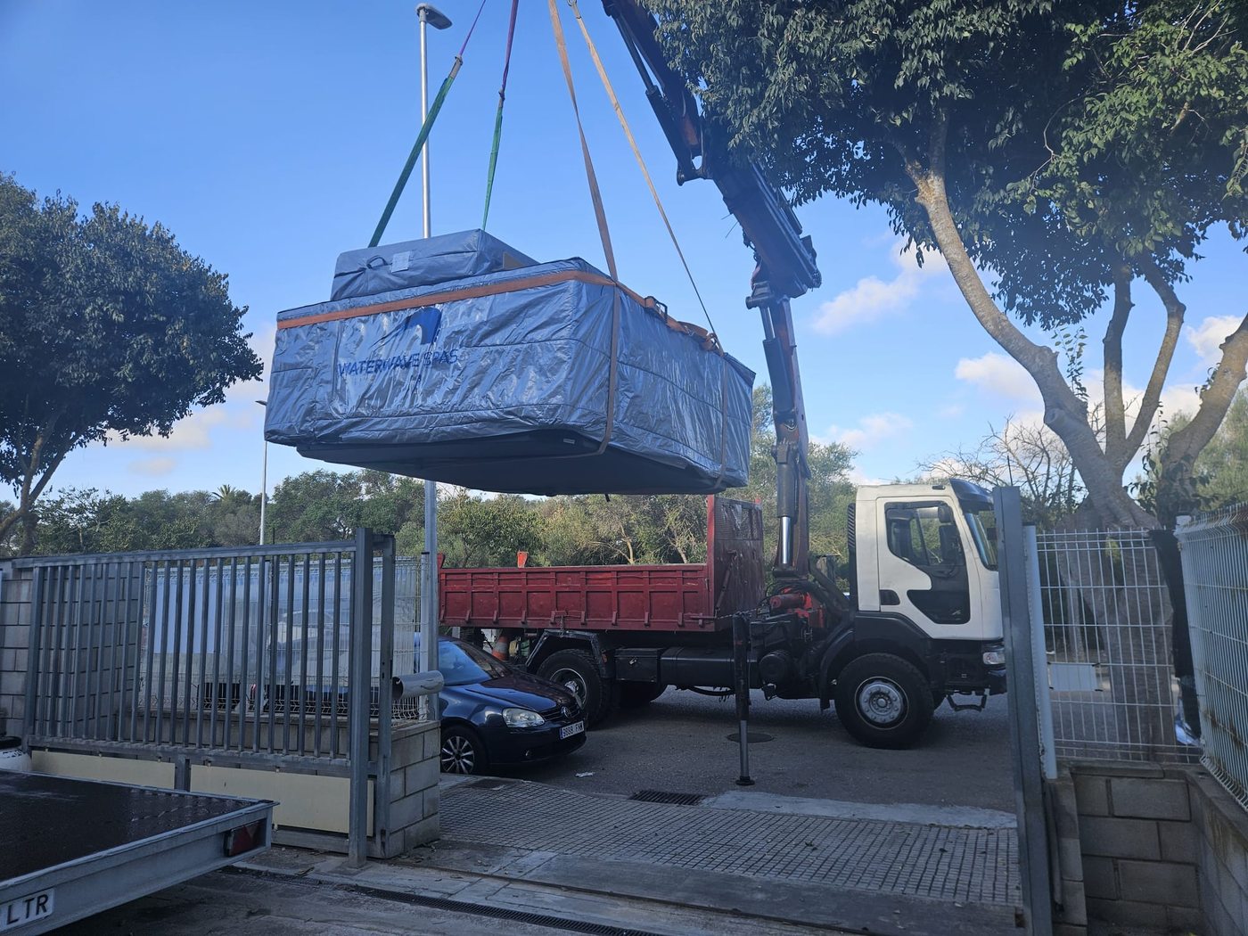 The Nizza II whirlpool on the crane hook lifting off the delivery truck at the entrance in Bunyola