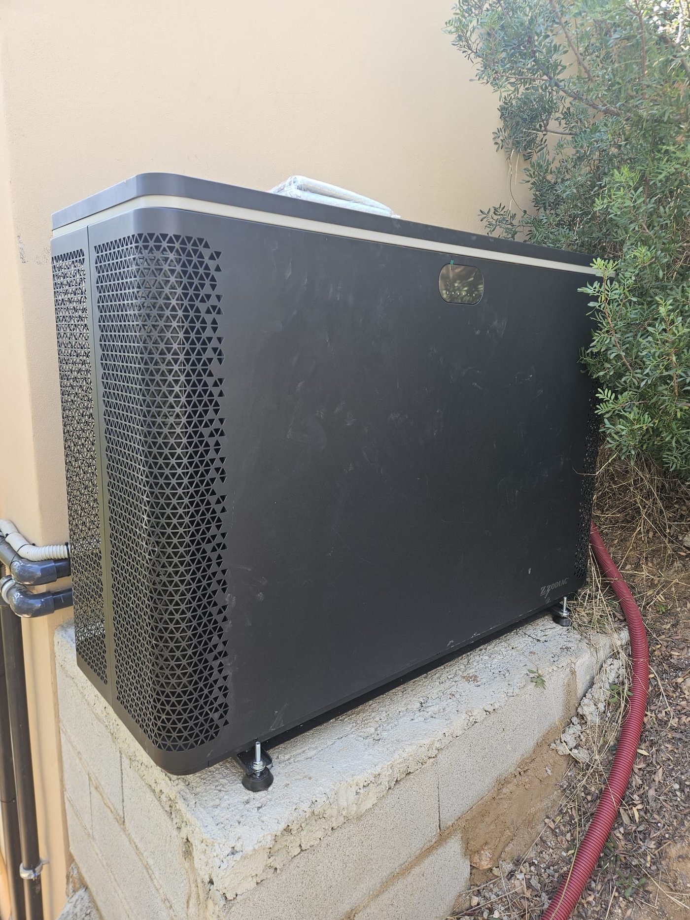 Heat pump installed on a level foundation behind the guest house, connected to the pool system