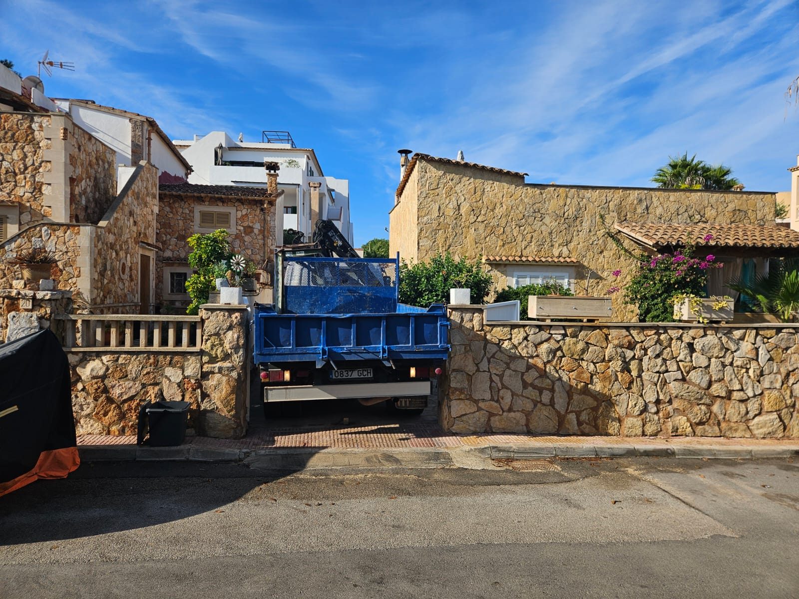 Crane truck positioned in the narrow lane beside the house