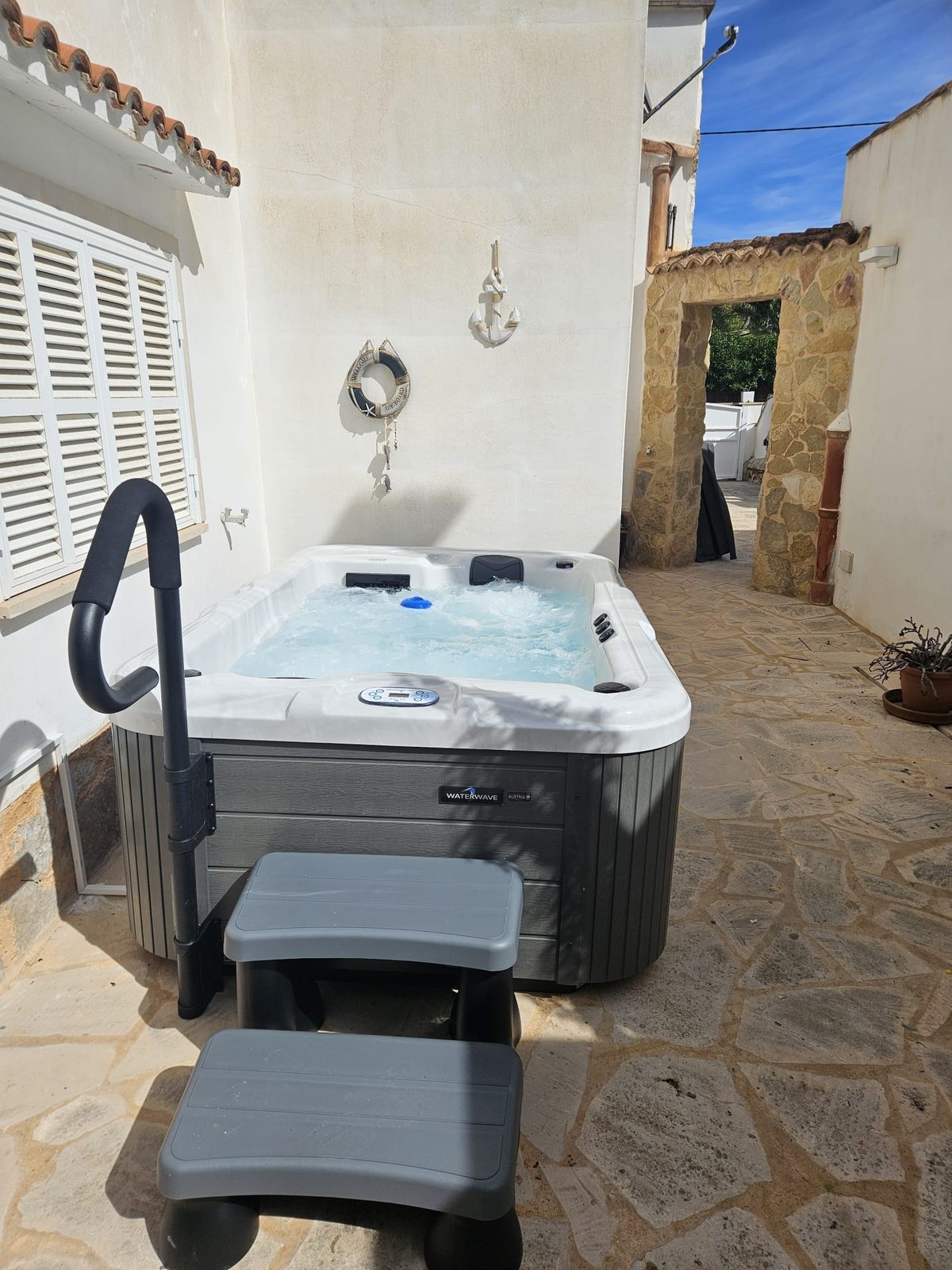 Finished low-profile Chicago whirlpool with handrail and step under the window in a tight courtyard in Cala Santany&iacute;, Mallorca